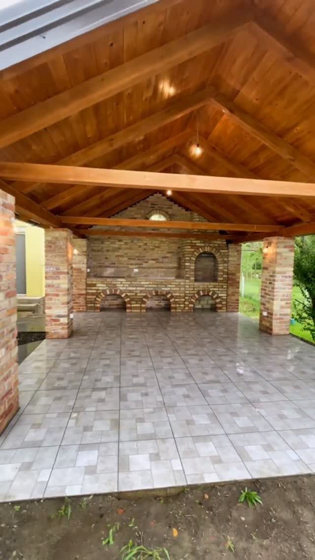A large brick barbecue structure with multiple arched openings under a wooden pavilion.