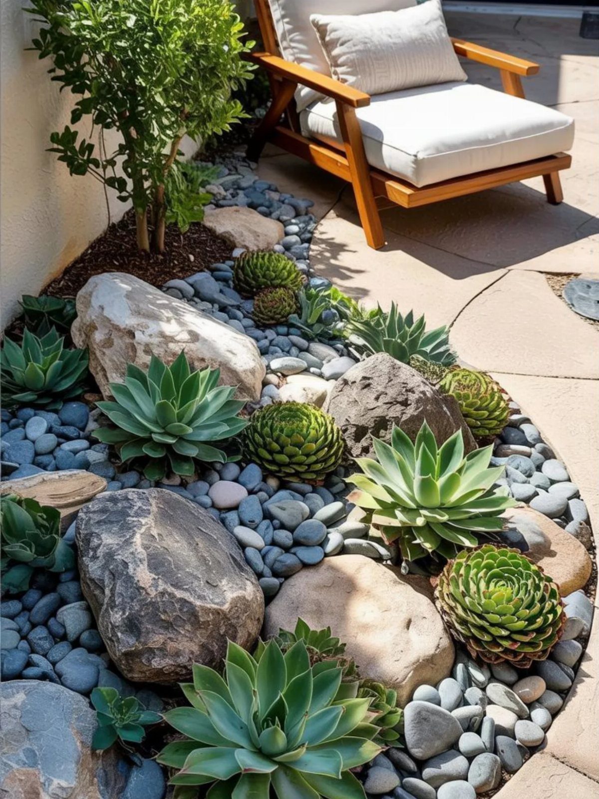 Succulent plants and large boulders nestled among smooth grey river stones in a landscaped garden.