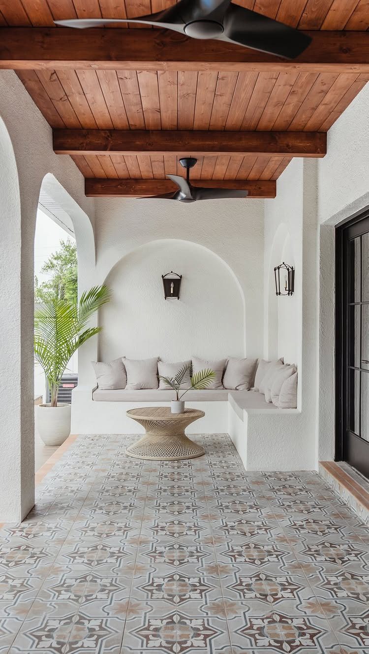 16 Backyard Patio Designs for Fire Pits, Pergolas & Outdoor Kitchens 8 Built-in L-shaped stucco seating with grey cushions under a wooden ceiling on a tiled patio.