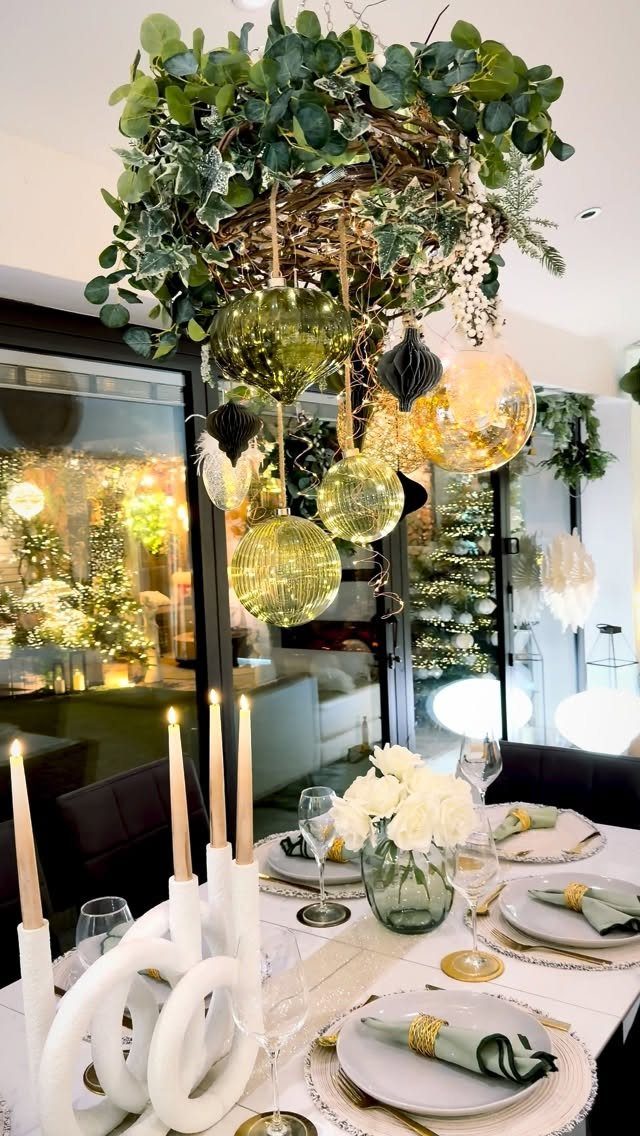 A green wreath with hanging gold ornaments suspended above a decorated dining table.