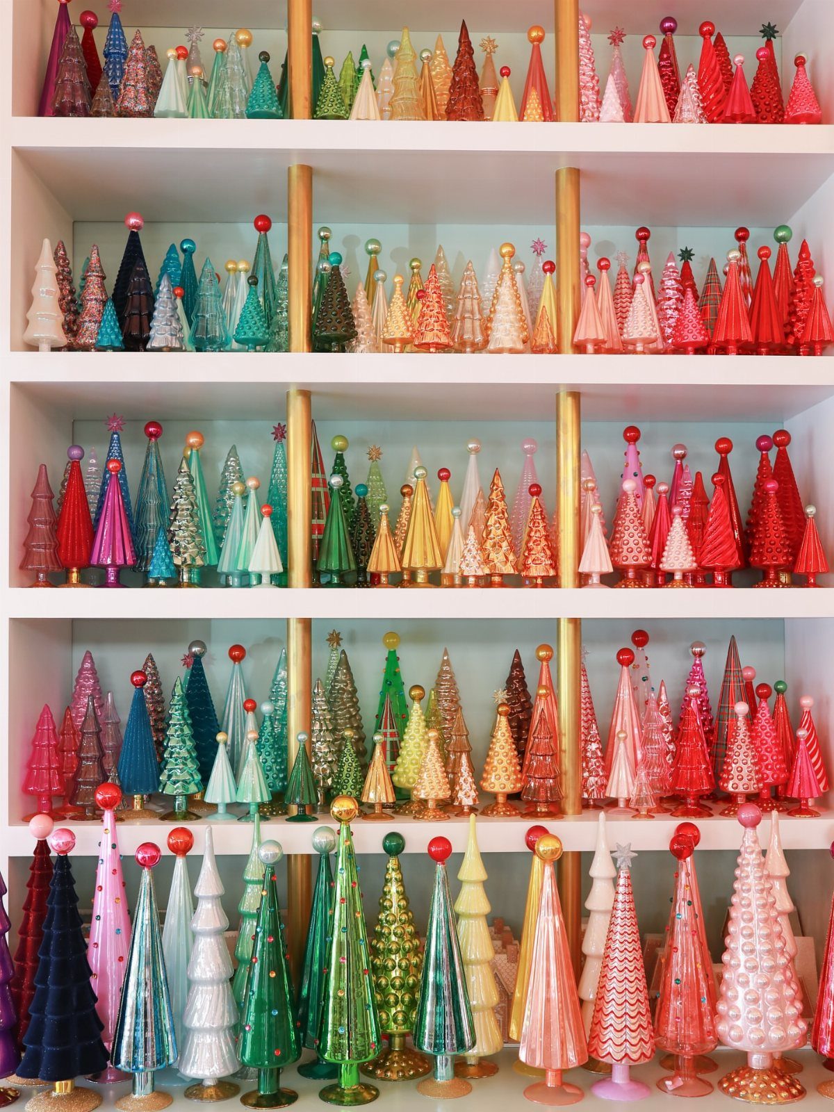 27 Christmas Display Ideas for Every Room of the Home 21 Rows of small, colorful, glittery decorative trees arranged on white shelving units.