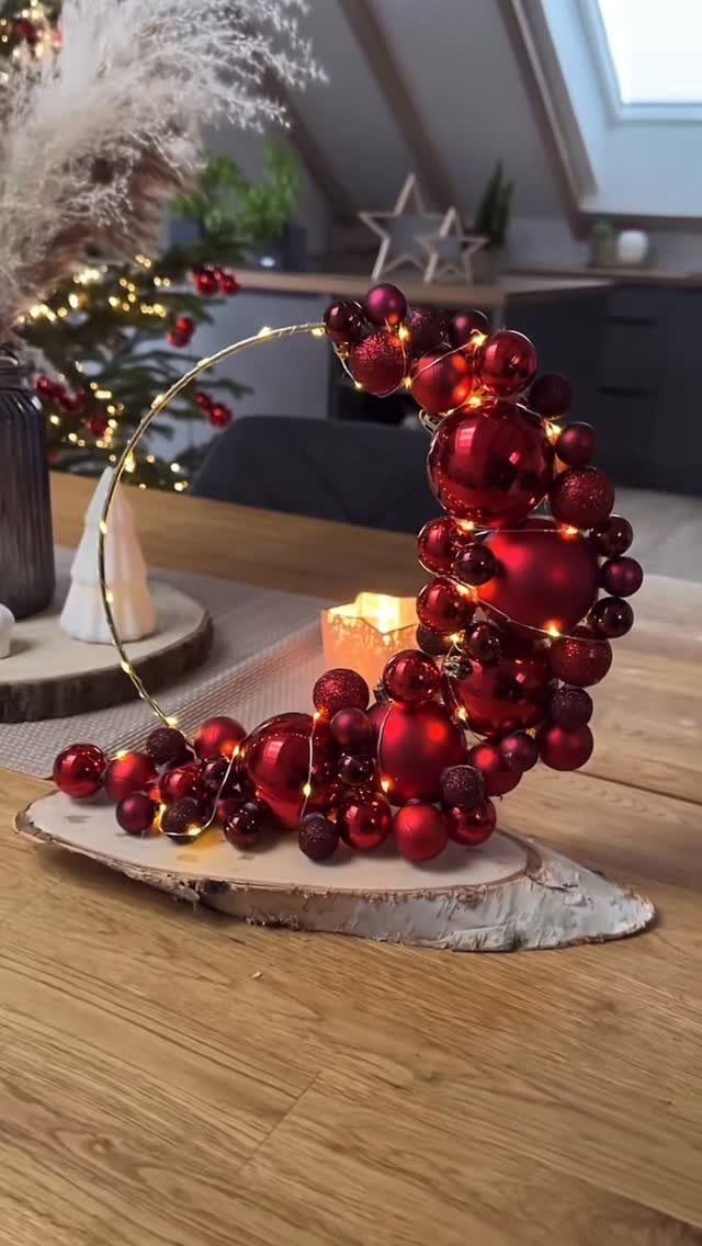 27 Christmas Display Ideas for Every Room of the Home 19 Red Christmas ornaments arranged in a crescent shape with twinkling fairy lights on a wooden base.