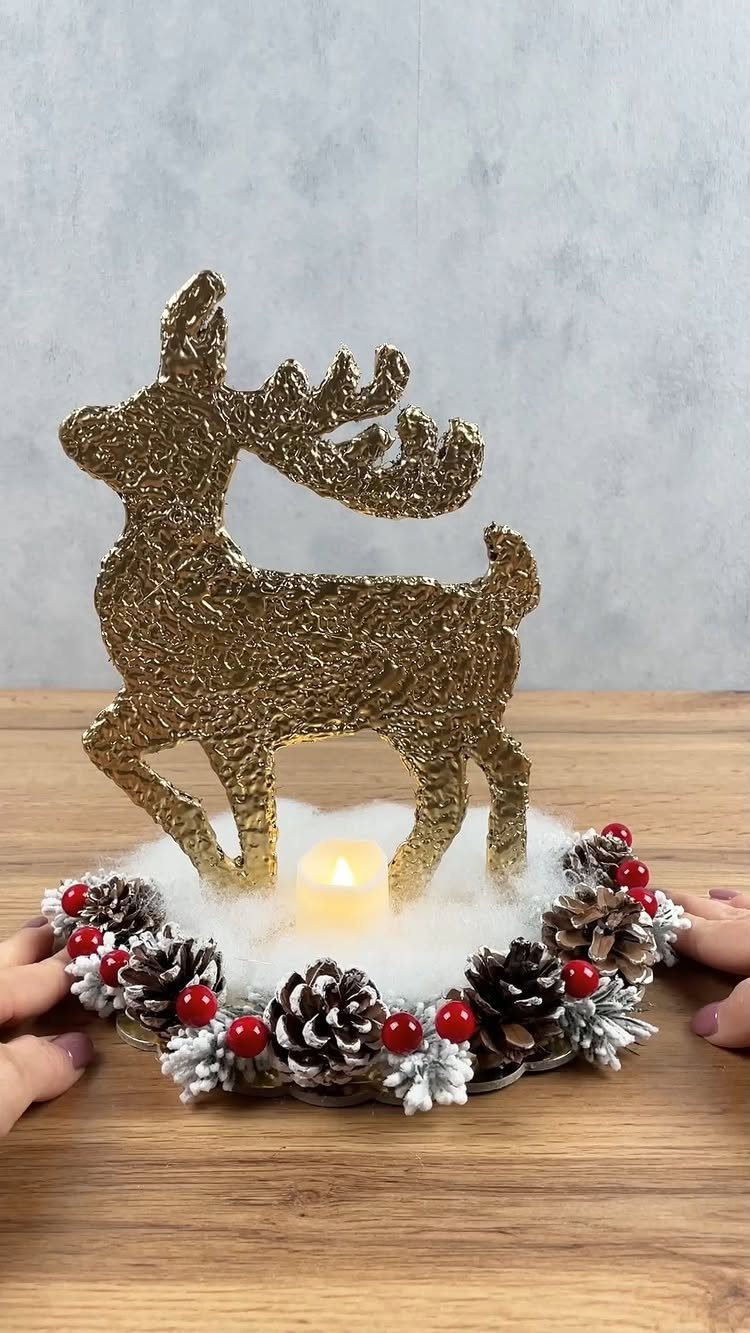 27 Christmas Display Ideas for Every Room of the Home 26 Gold glitter reindeer silhouette standing behind a pine cone wreath with red berries and a candle.