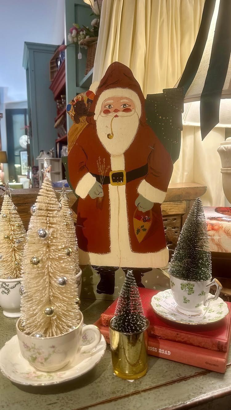 27 Christmas Display Ideas for Every Room of the Home 9 Small decorative bristled trees sitting inside vintage teacups on a tabletop with a Santa cutout.