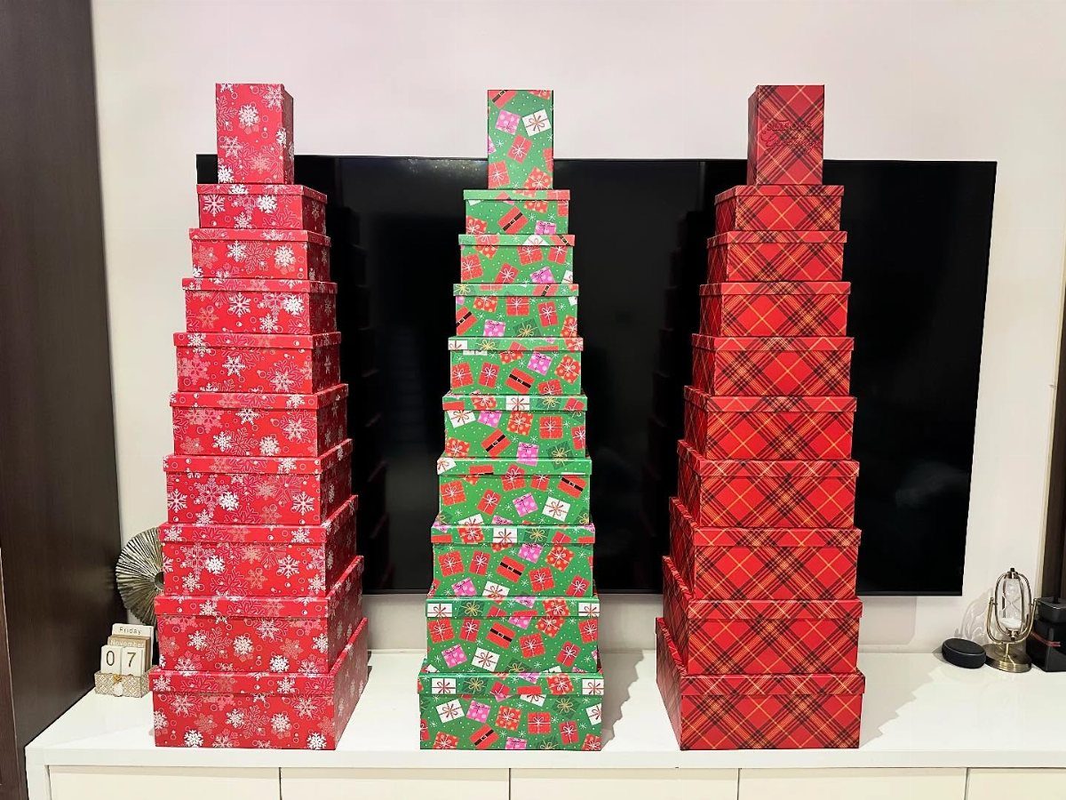 Three stacks of patterned gift boxes arranged in triangular tree shapes on a white sideboard.