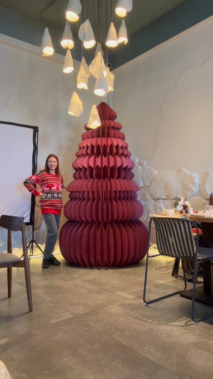 A large red tiered paper sculpture shaped like a Christmas tree in a room.
