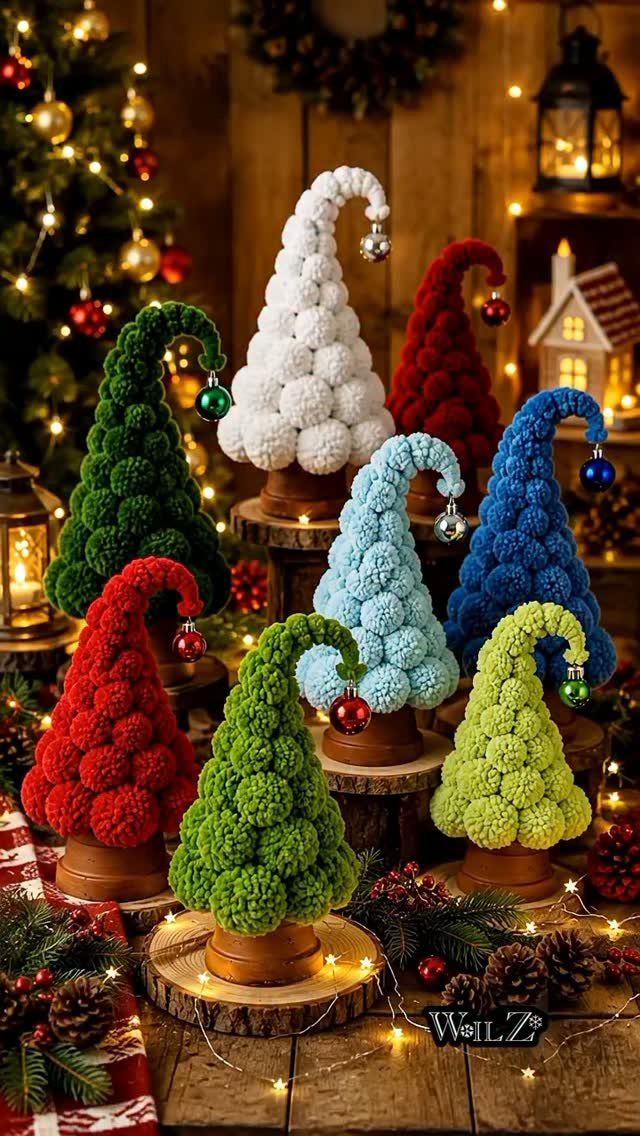 Colorful pom-pom trees in various colors sitting on wooden bases with ornaments.