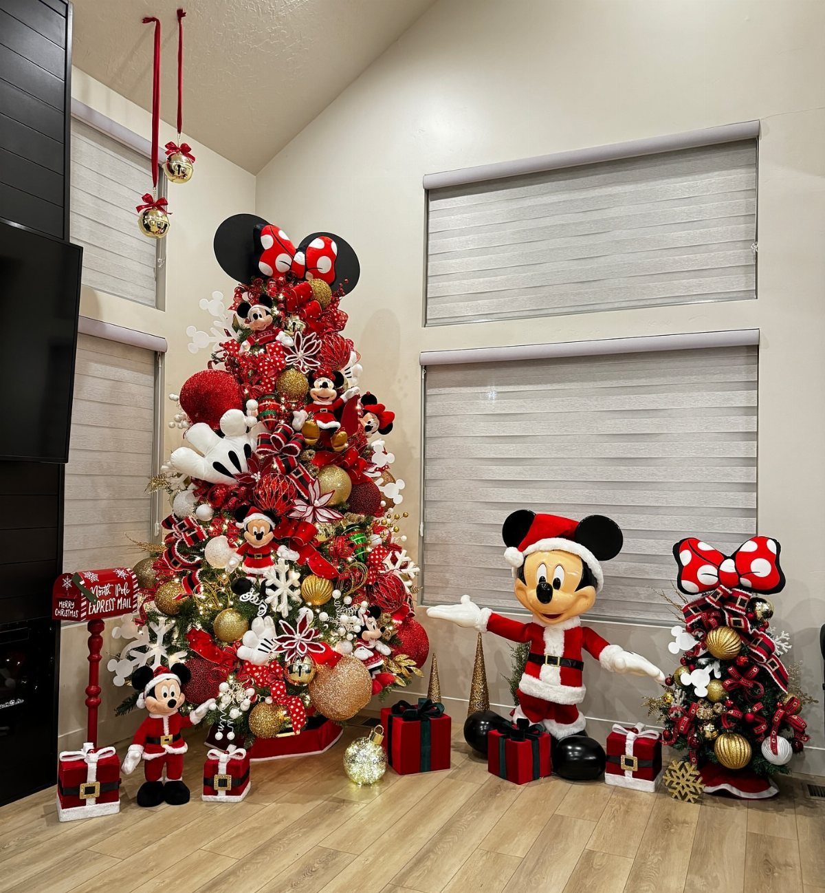Christmas Tree Decor Ideas for 2025: 17 Fresh Styles from Coastal to Candyland 13 Red Christmas tree decorated with Mickey Mouse ornaments, snowflakes, and gold baubles next to a Mickey Santa figure.