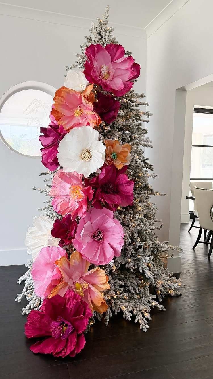 Christmas Tree Decor Ideas for 2025: 17 Fresh Styles from Coastal to Candyland 10 Flocked Christmas tree decorated with large, colorful pink, white, and orange artificial flowers.