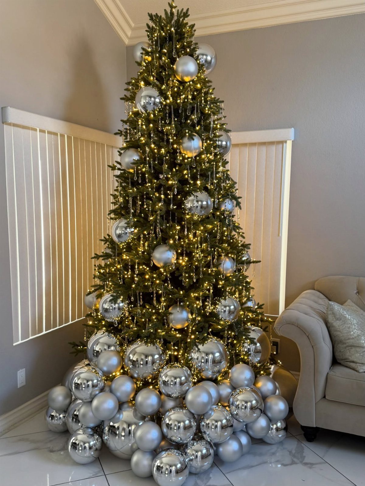 Christmas Tree Decor Ideas for 2025: 17 Fresh Styles from Coastal to Candyland 3 A decorated Christmas tree with silver ornaments and warm fairy lights on a white floor.