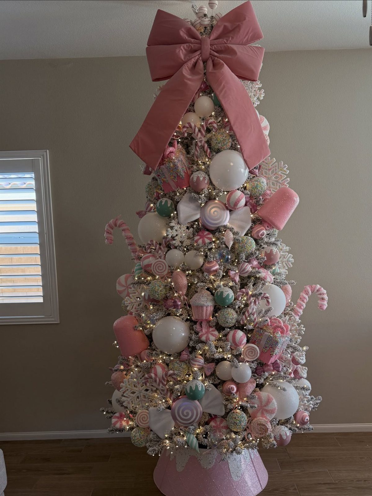 Christmas Tree Decor Ideas for 2025: 17 Fresh Styles from Coastal to Candyland 6 A pink and white Christmas tree decorated with candy motifs and large pink bows.