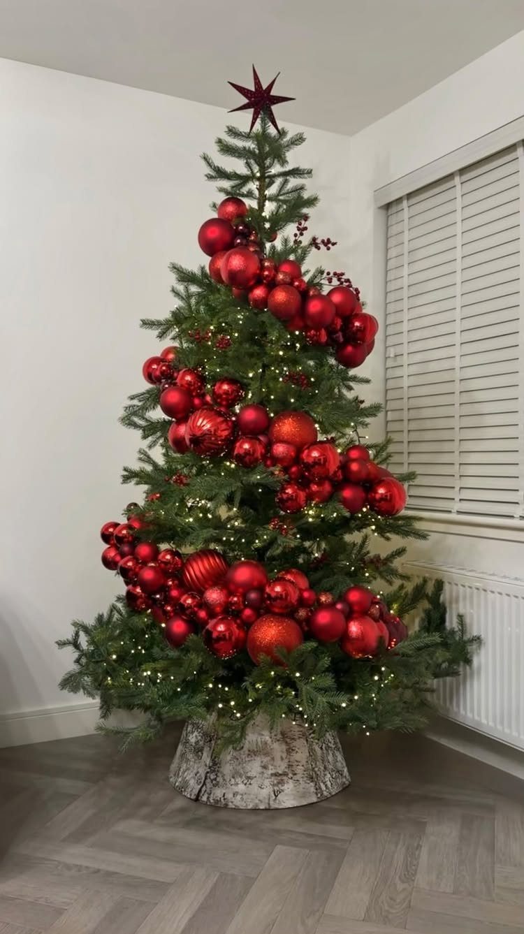 Christmas Tree Decor Ideas for 2025: 17 Fresh Styles from Coastal to Candyland 14 A green Christmas tree decorated with many red ornaments and a red star topper.