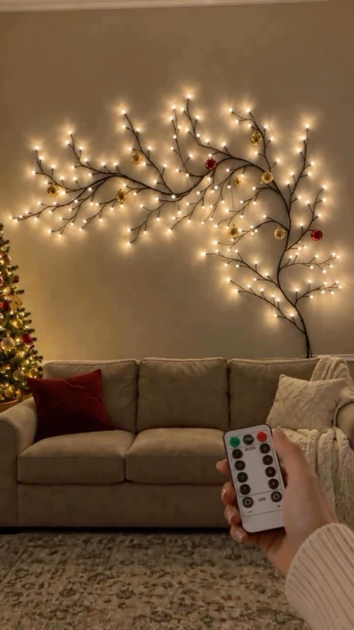 Christmas Wall Decor Ideas: 9 Ways to Dress Vertical Space 4 A lit branch wall decoration hangs above a neutral colored sofa in a living room.