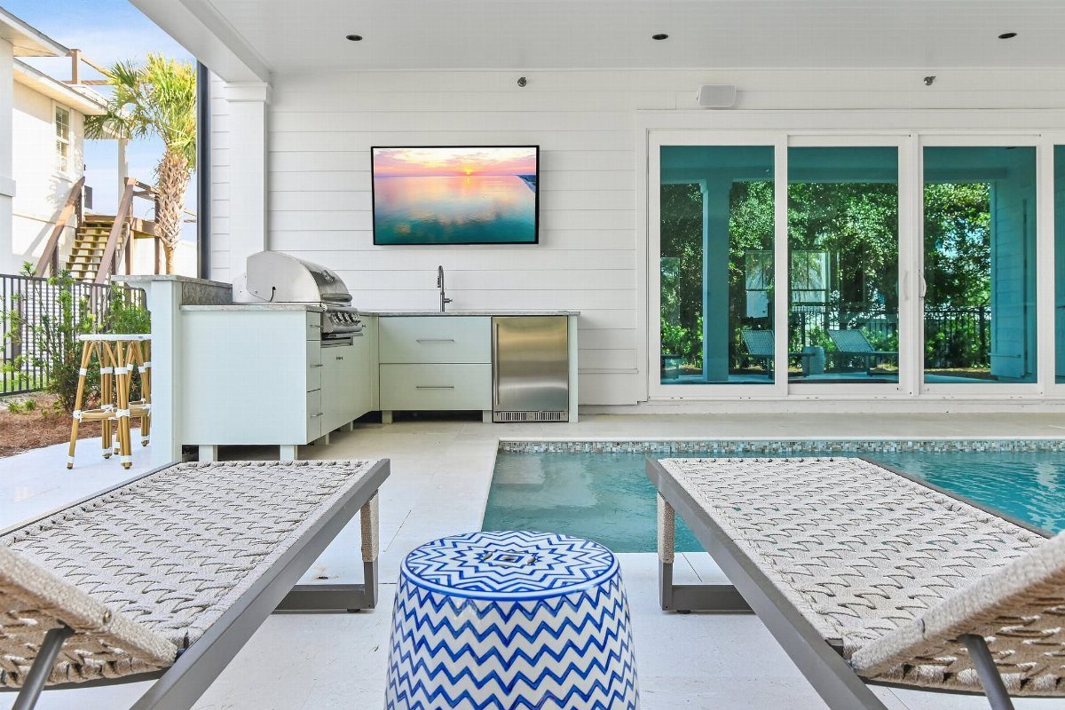 Coastal Outdoor Kitchen and 7 Ideas for Beachside Cooking Spaces 1 Light blue outdoor kitchen island with a grill and sink next to a swimming pool.