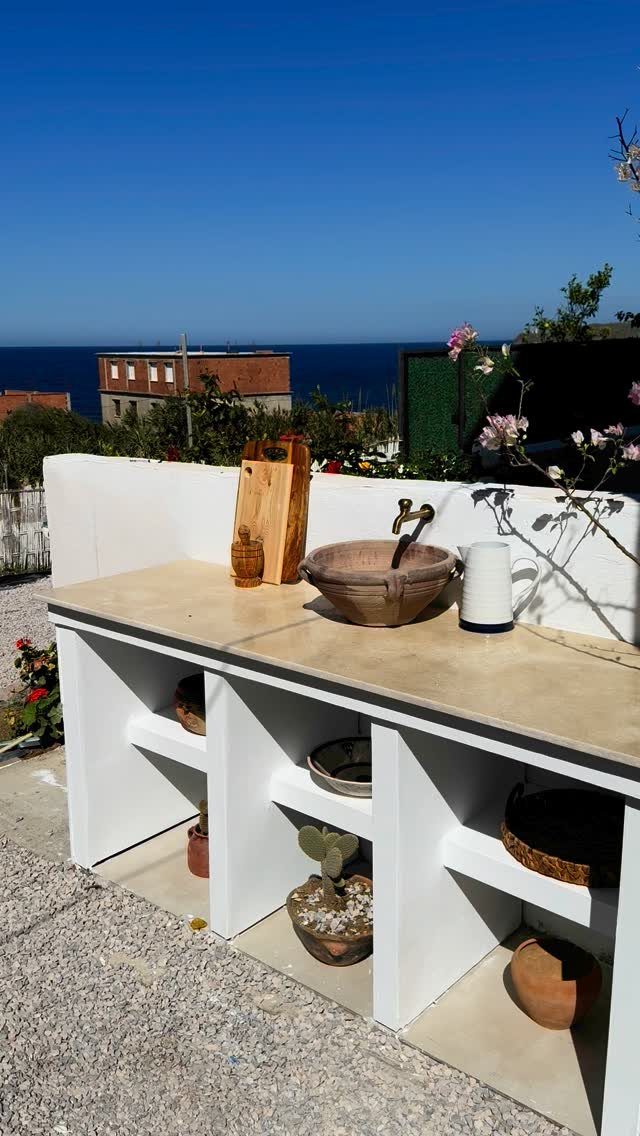 Coastal Outdoor Kitchen and 7 Ideas for Beachside Cooking Spaces 5 White outdoor kitchen counter with a stone sink and cutting boards overlooking the ocean.