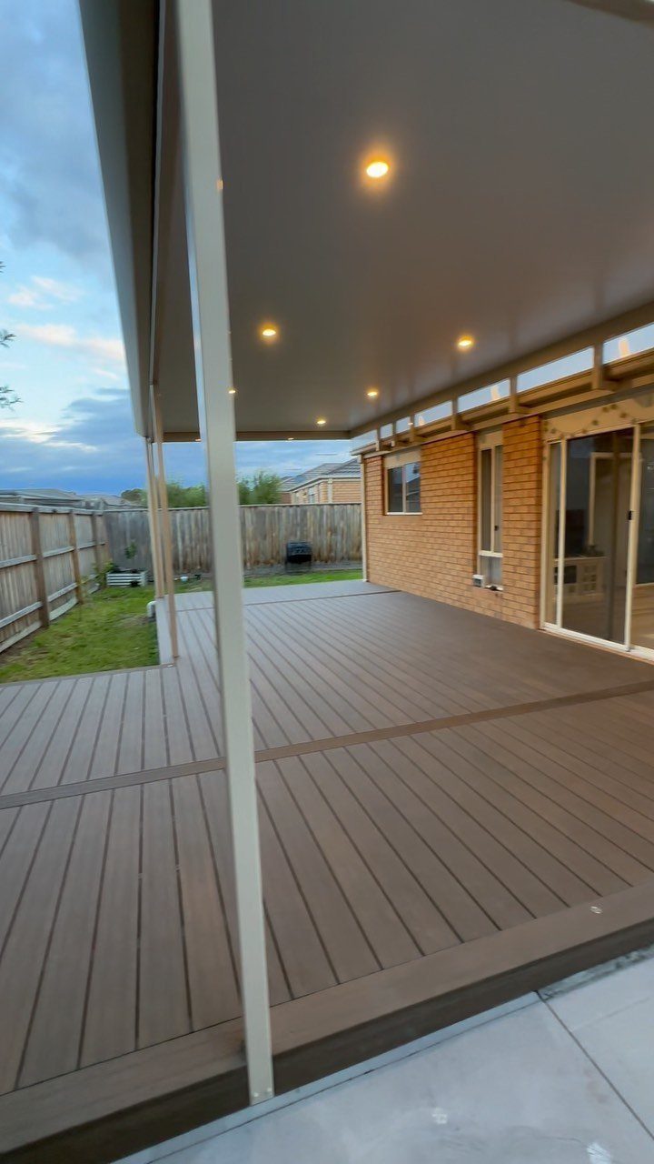 Composite Wood Deck 13 Ideas for Plans, Patterns and Colors 7 A brown composite wood deck installed under a covered patio next to a brick house.