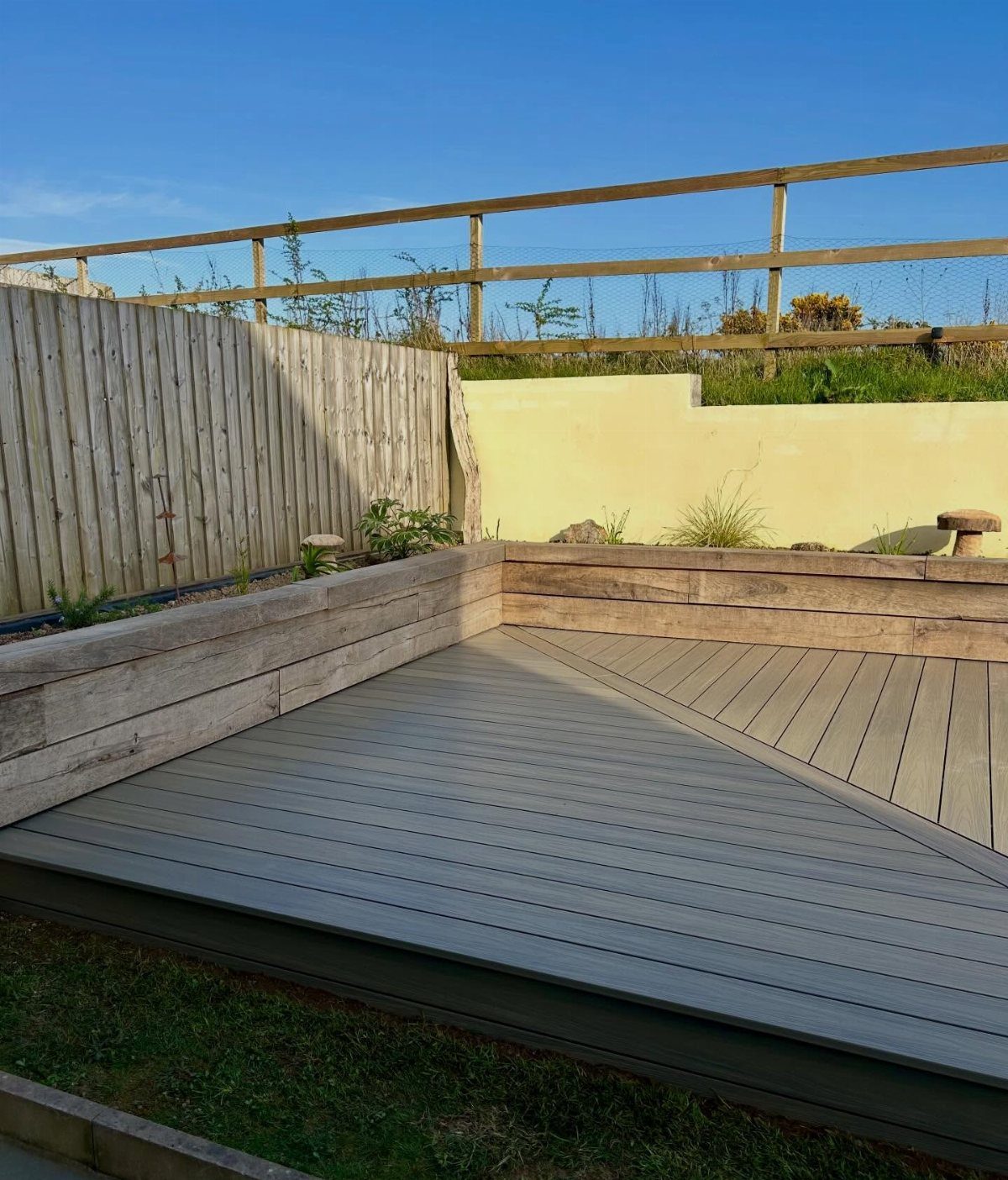 Composite Wood Deck 13 Ideas for Plans, Patterns and Colors 13 Grey composite wood decking with a geometric pattern installed in a garden with wooden retaining walls.