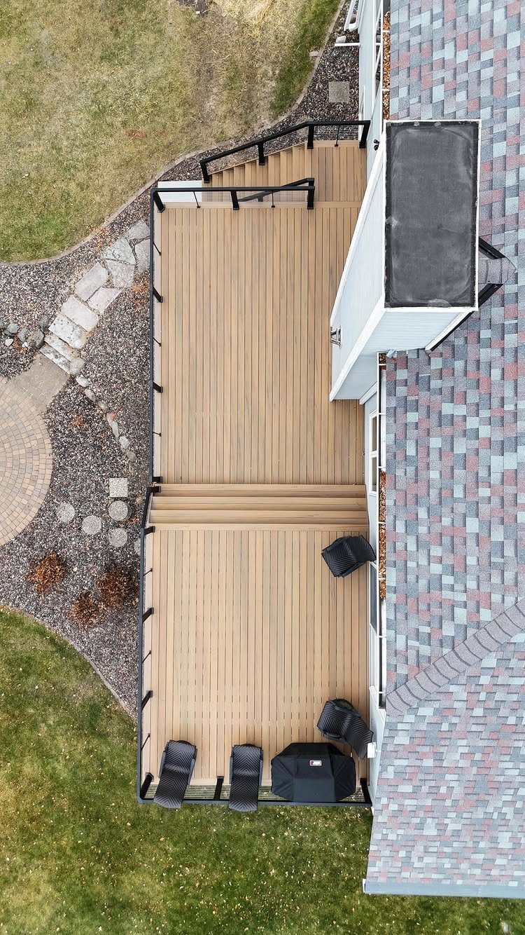 Composite Wood Deck 13 Ideas for Plans, Patterns and Colors 5 Aerial view of a multi-level light brown composite wood deck attached to a house with black railings.