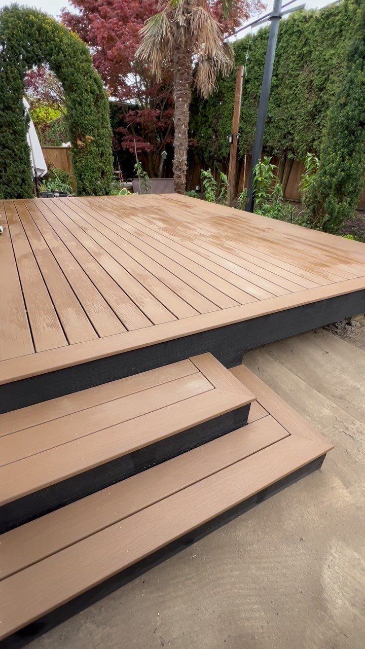 Composite Wood Deck 13 Ideas for Plans, Patterns and Colors 9 Tan composite wood deck with dark grey trim and steps in a lush backyard setting.
