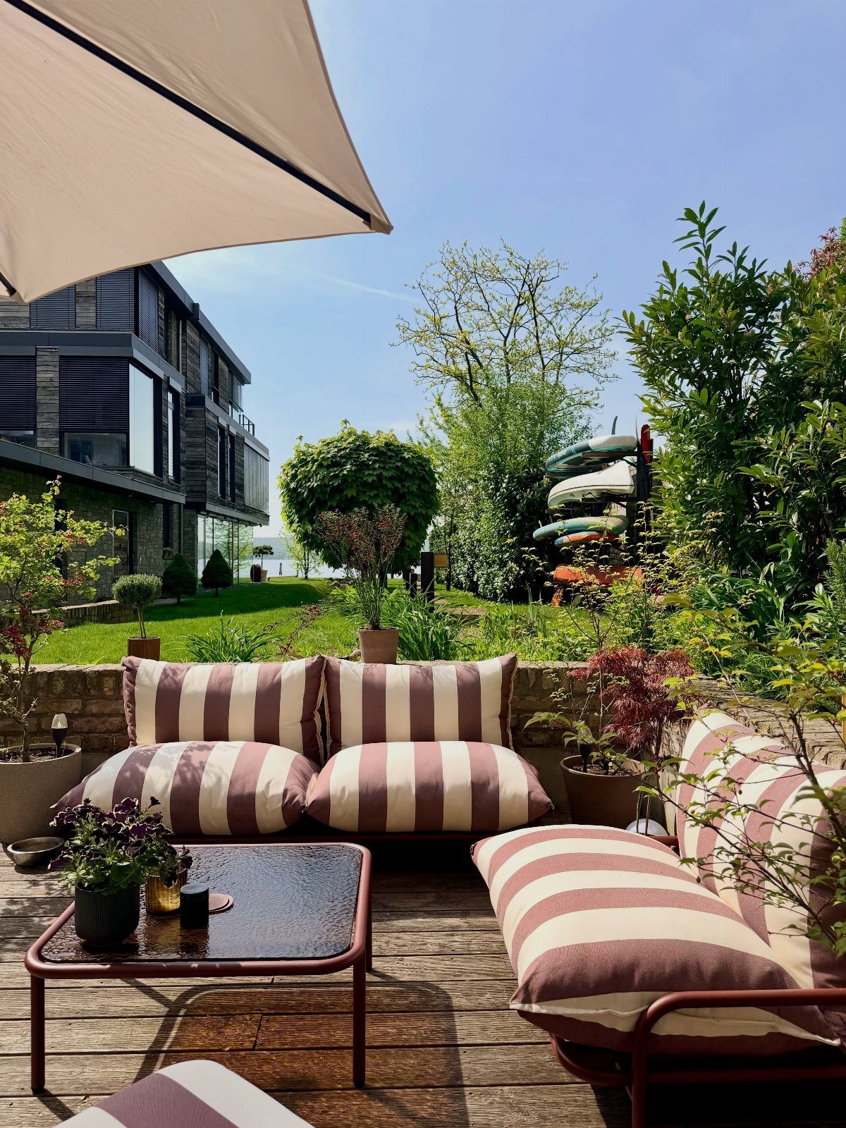 Striped lounge cushions and a small coffee table arranged on a wooden deck outdoors.