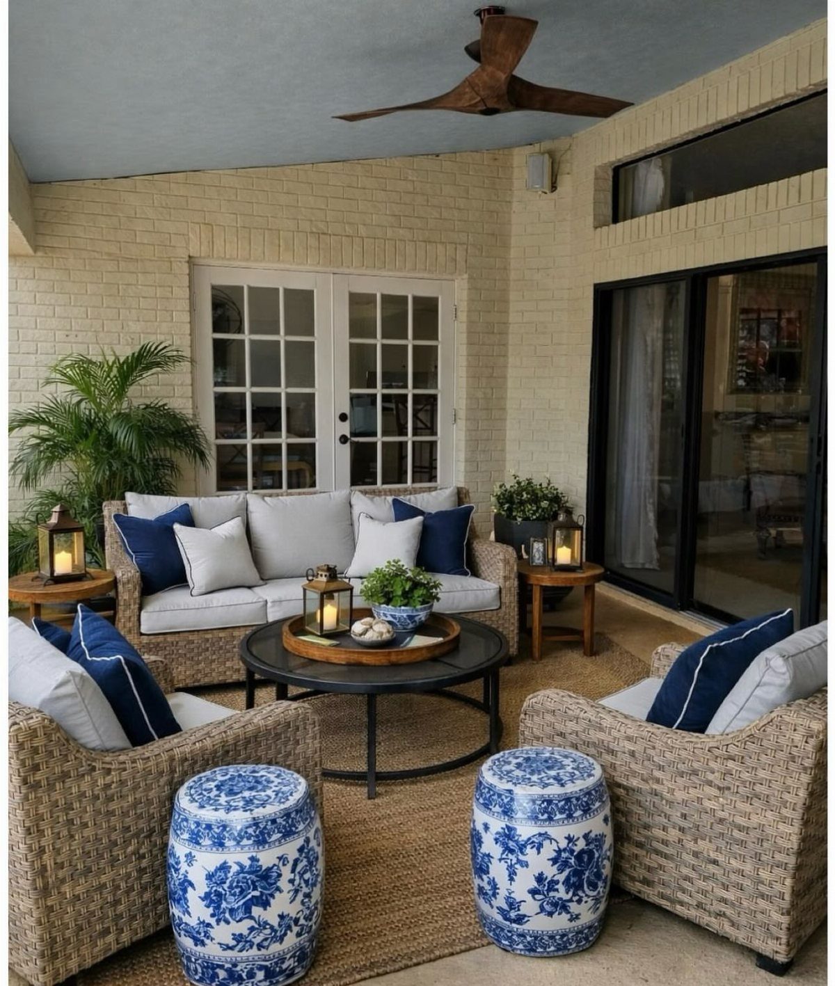 Wicker patio furniture with navy blue and white decorative pillows on a covered deck.