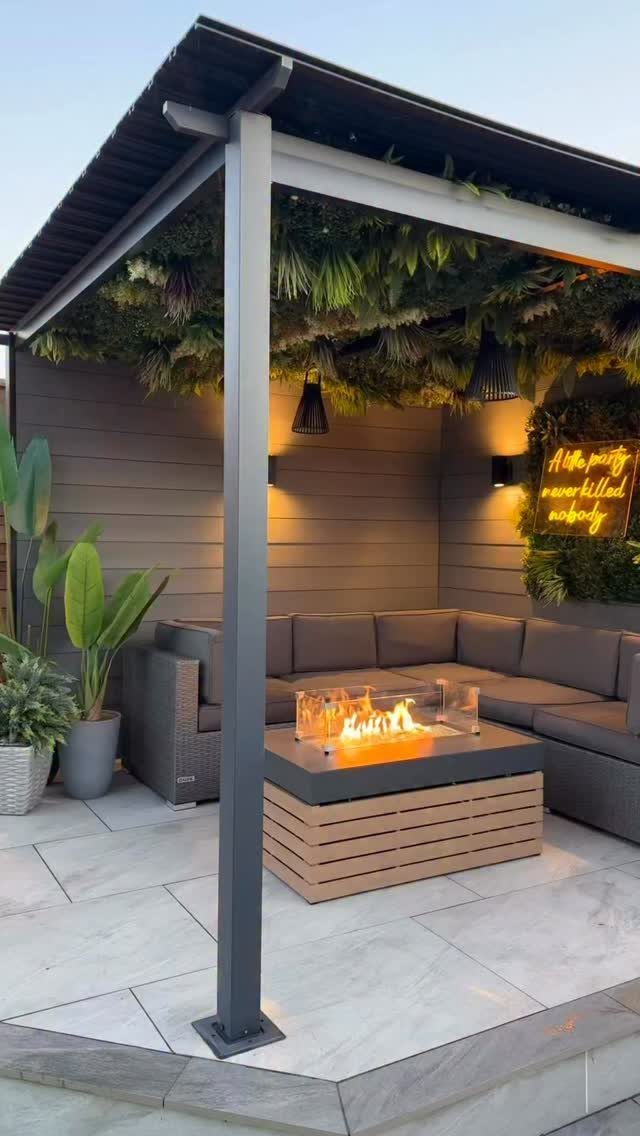 A modern outdoor seating area with a lit fire pit and grey sectional sofa.