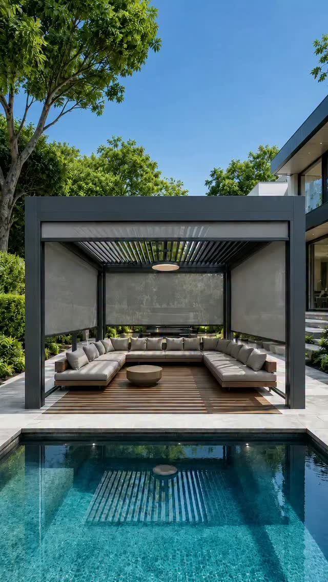 A modern black pergola with grey screens shading a large outdoor sectional sofa by a pool.