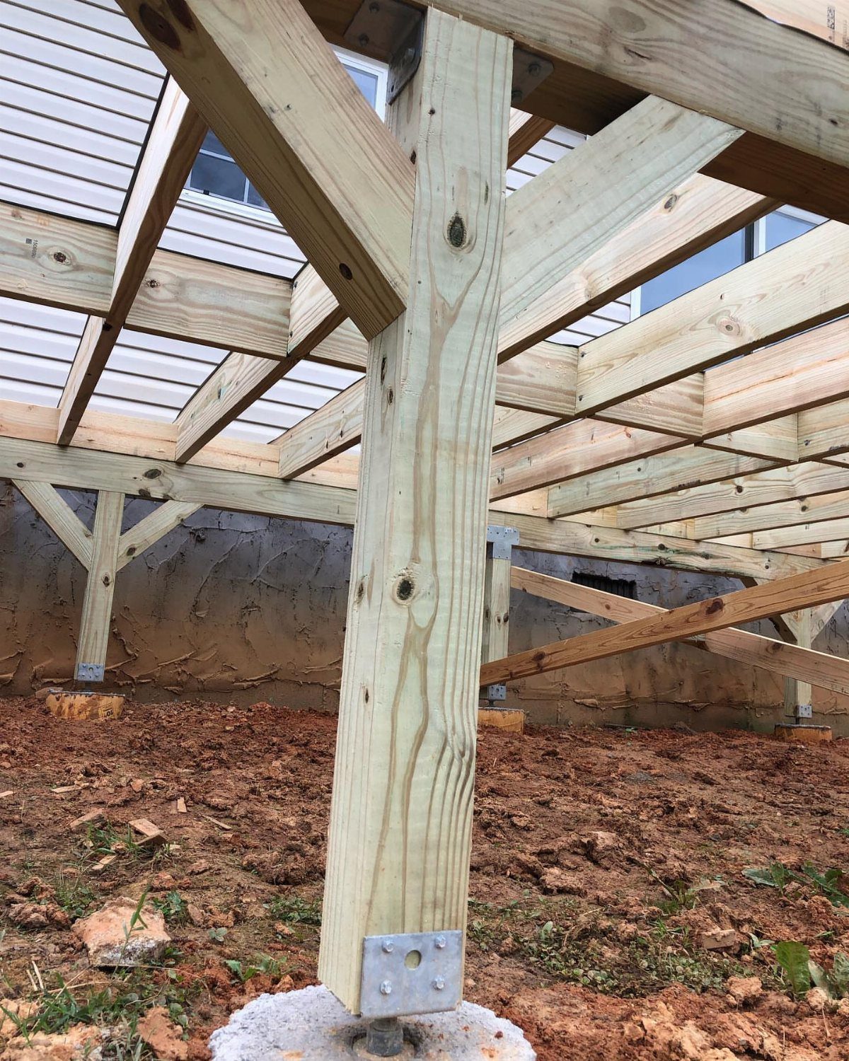 Wooden deck framing structure with support posts and beams installed on concrete footings.