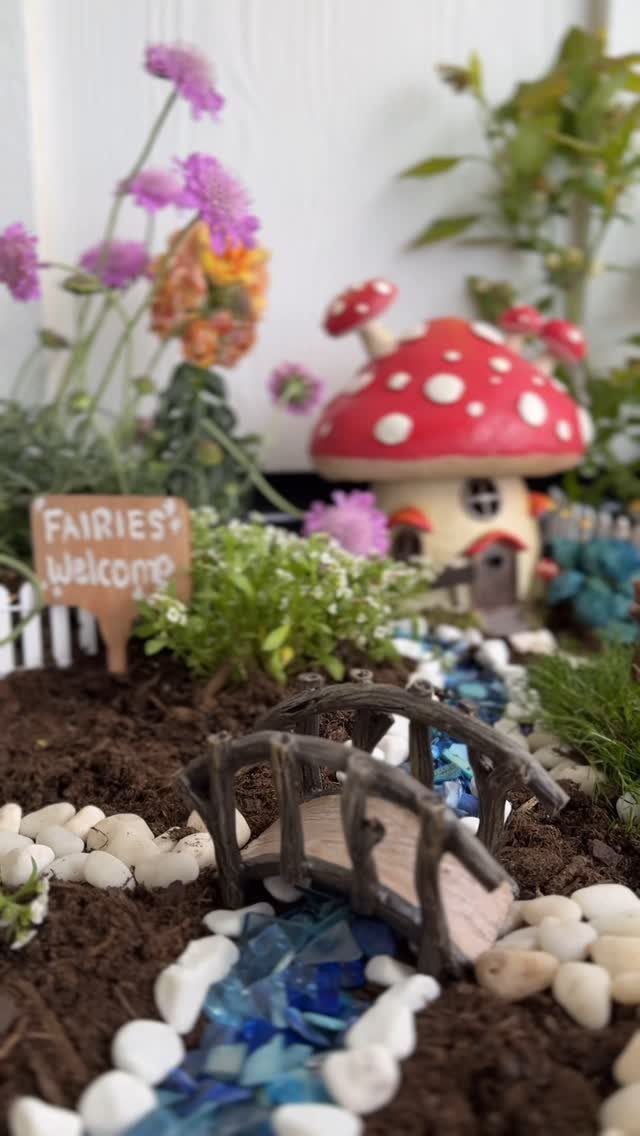 8 DIY Garden Projects for Fairy Gardens, Raised Beds and Outdoor Play 1 A miniature fairy garden with a mushroom house, small bridge, and blue pebble stream.