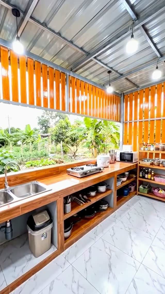 Wooden outdoor kitchen counter featuring multiple open shelves filled with various kitchenware and bowls.