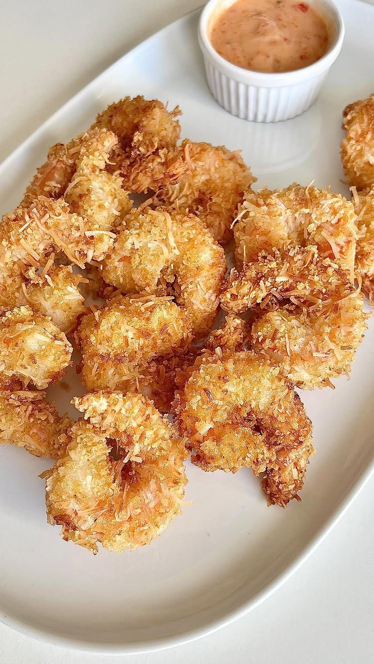 32 Easy Christmas Party Ideas for Food, Drinks, and Hosting in 2026 15 Golden-brown coconut shrimp served on a white platter with a side of dipping sauce.