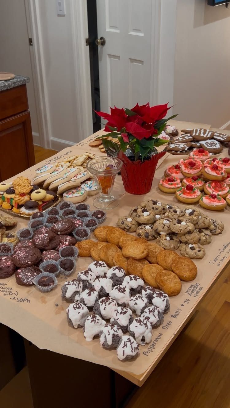 32 Easy Christmas Party Ideas for Food, Drinks, and Hosting in 2026 12 Assorted Christmas cookies and a red poinsettia plant spread across a large table.