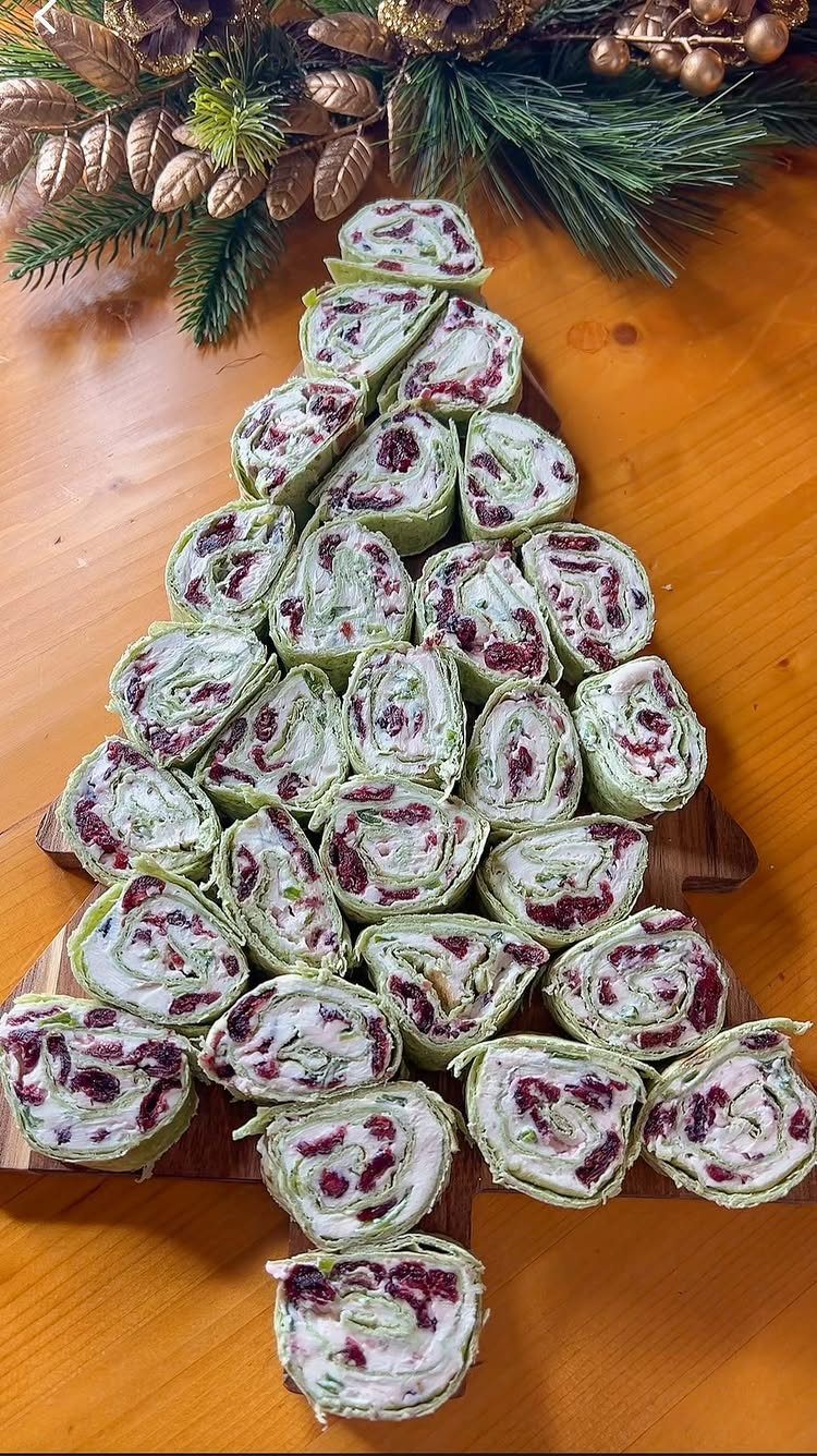 32 Easy Christmas Party Ideas for Food, Drinks, and Hosting in 2026 28 Spinach and cranberry pinwheel wraps arranged in a Christmas tree shape on a wooden platter.