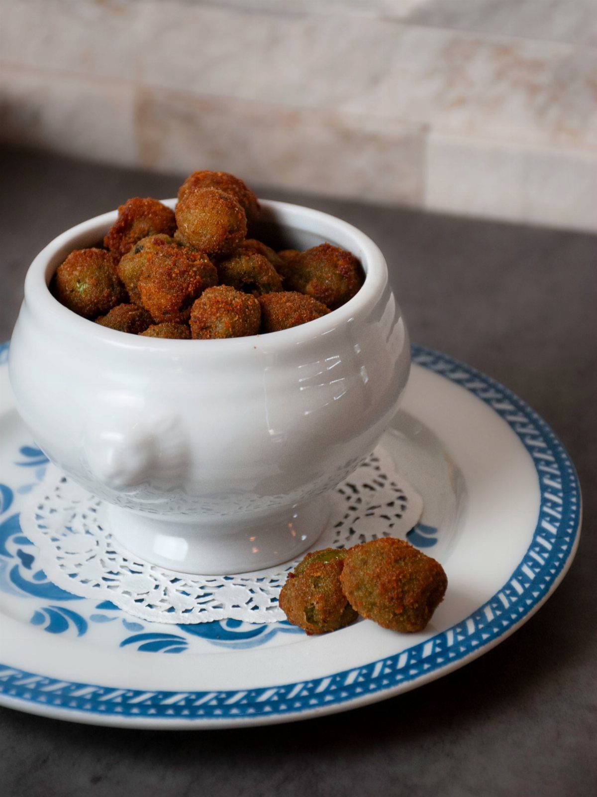 32 Easy Christmas Party Ideas for Food, Drinks, and Hosting in 2026 5 Breaded crispy olives served in a white ceramic bowl on a patterned plate.