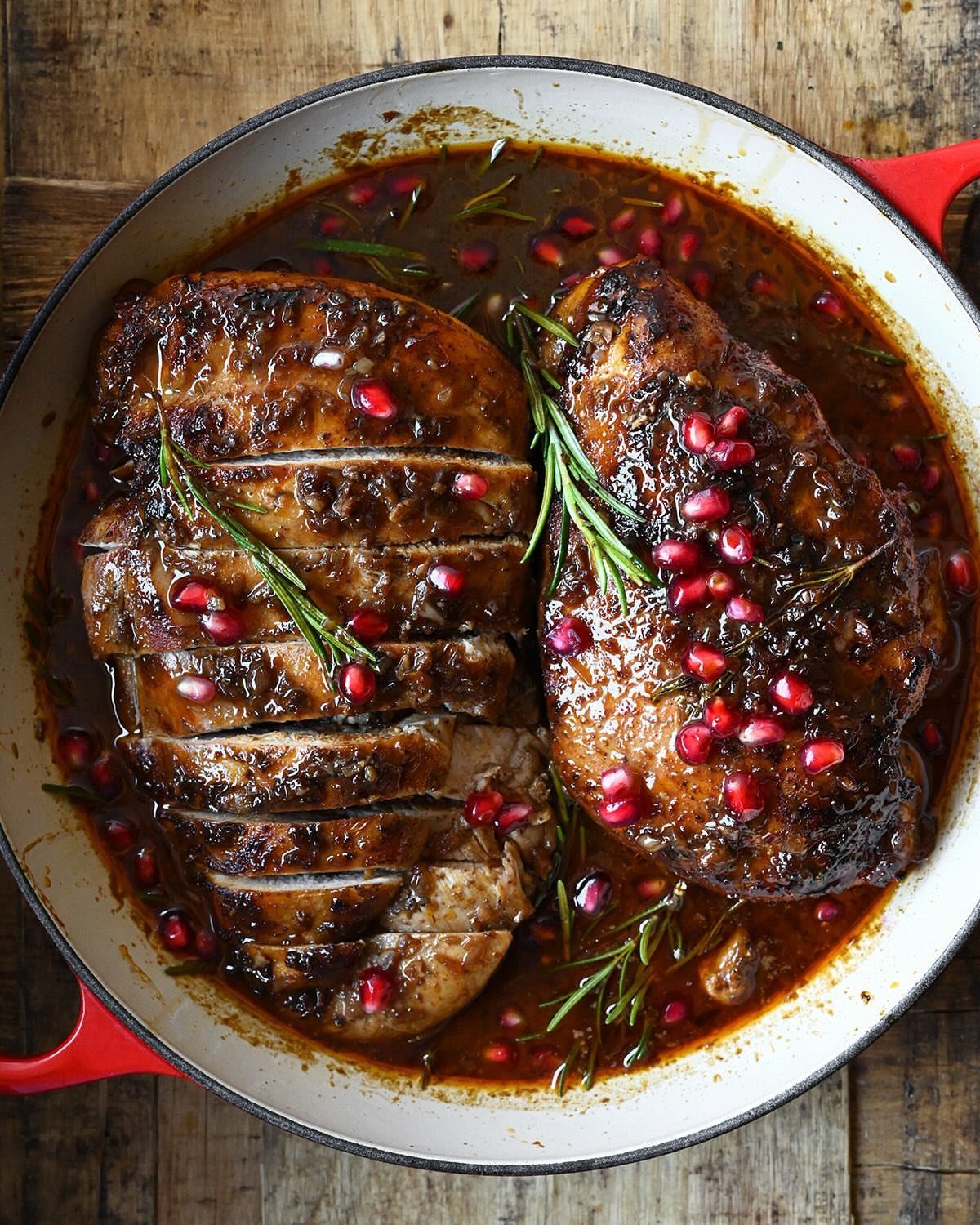 32 Easy Christmas Party Ideas for Food, Drinks, and Hosting in 2026 20 Glazed pork roast with pomegranate seeds and rosemary sprigs in a white pan.