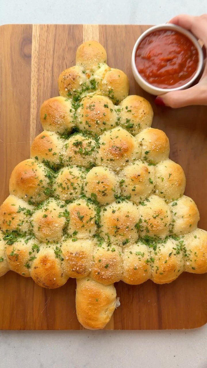 32 Easy Christmas Party Ideas for Food, Drinks, and Hosting in 2026 3 Garlic herb pull-apart bread shaped like a Christmas tree on a wooden board with red sauce.