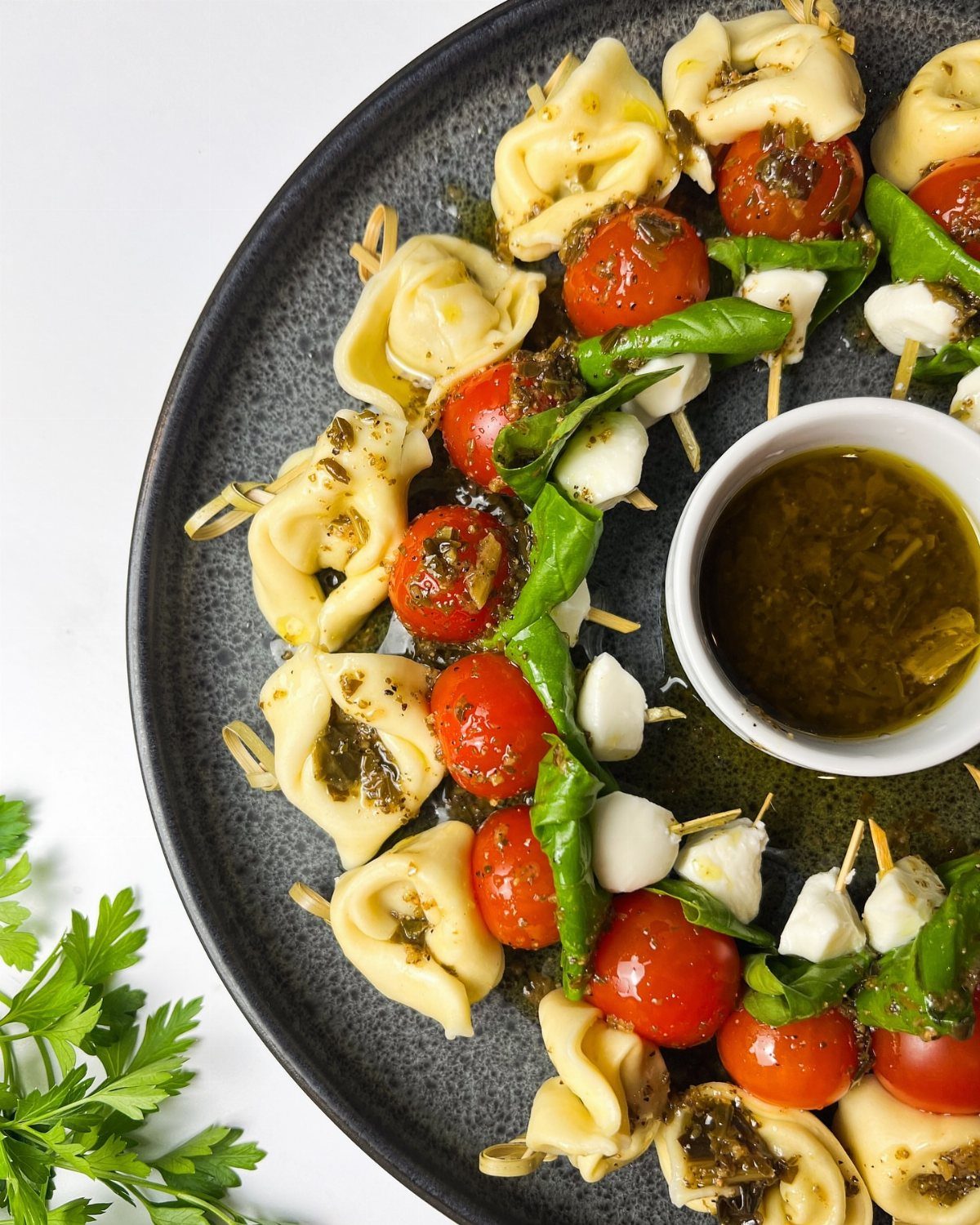 32 Easy Christmas Party Ideas for Food, Drinks, and Hosting in 2026 19 Tortellini skewers with cherry tomatoes, basil, and mozzarella served with a side of pesto sauce.