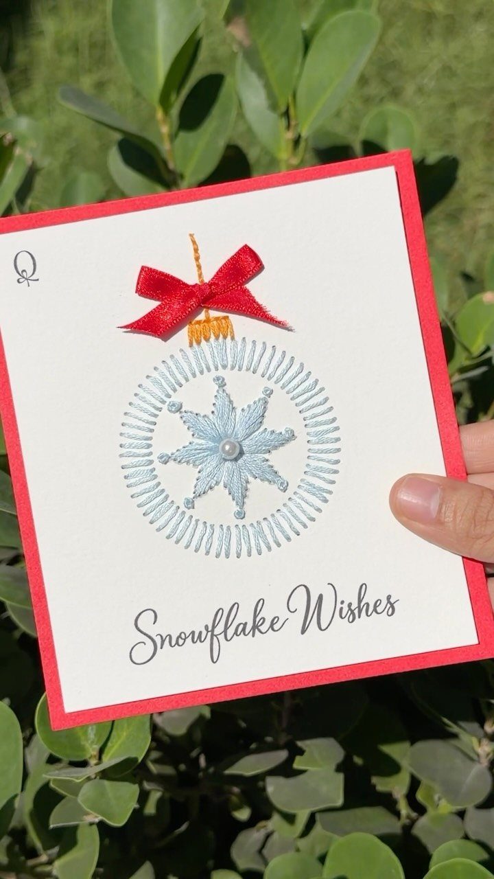 17 Easy DIY Christmas Gifts: Handmade Presents for Every List 7 A hand holding a white Christmas card with red borders and an embroidered snowflake ornament design.