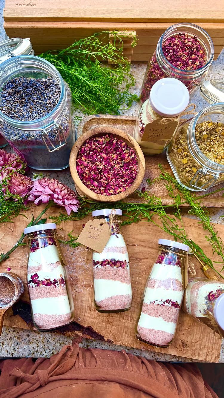 Glass bottles filled with layered pink and white bath salts and dried rose petals.