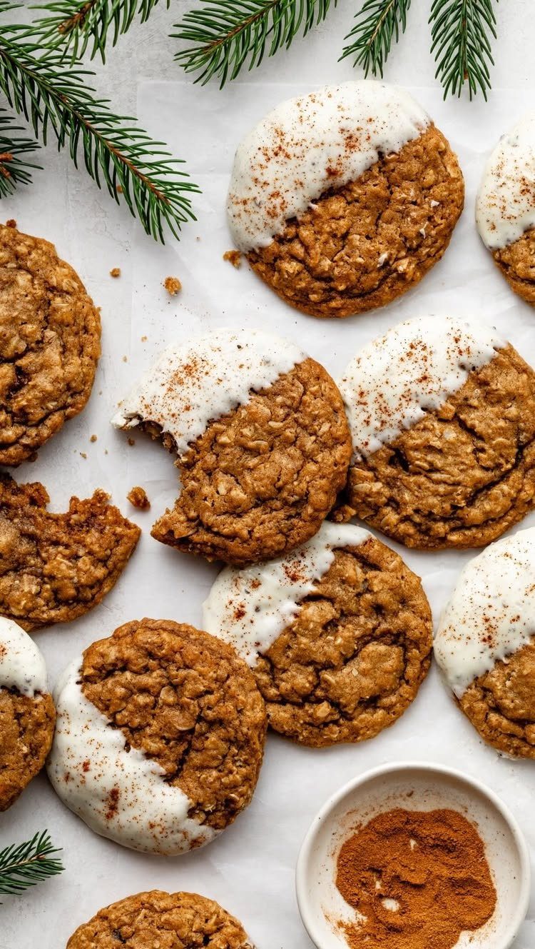 Oatmeal cookies dipped in white icing and sprinkled with cinnamon on white parchment paper.