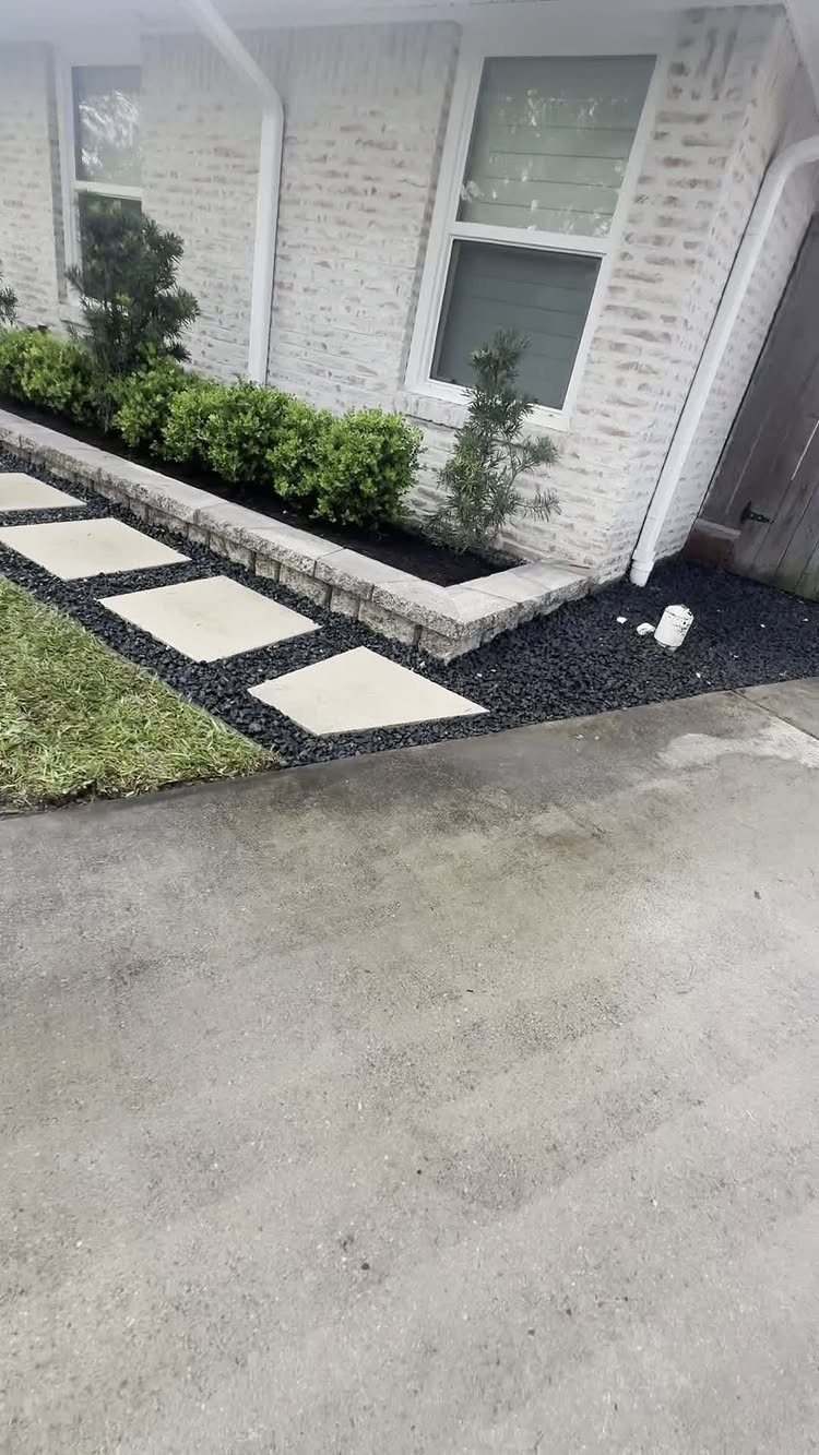 7 Easy Landscaping Ideas for a Cleaner, Lower-Maintenance Yard 6 Square concrete stepping stones create a simple pathway through dark mulch in a residential garden bed.