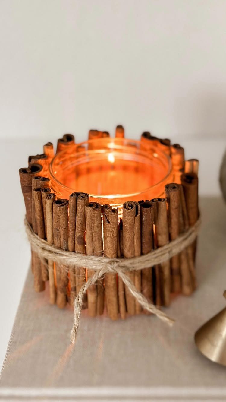A lit tea light candle surrounded by cinnamon sticks tied with twine.