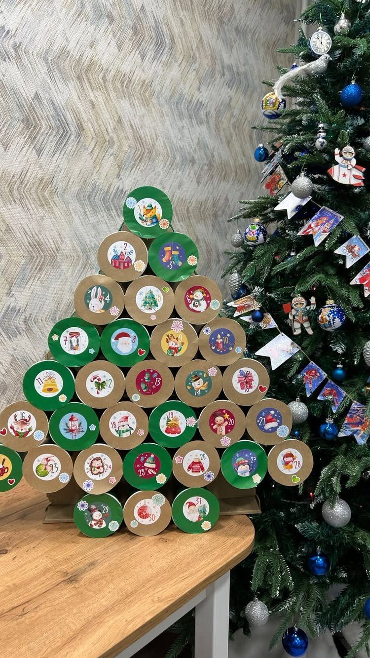 A Christmas tree constructed from decorated paper cups sitting on a wooden table.