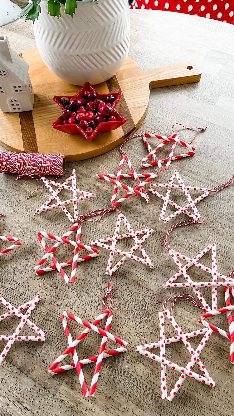 Red and white patterned paper straw star ornaments scattered on a light wooden tabletop.