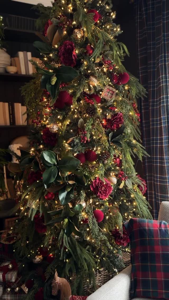 A decorated Christmas tree with red flowers, gold ornaments, and warm glowing lights.