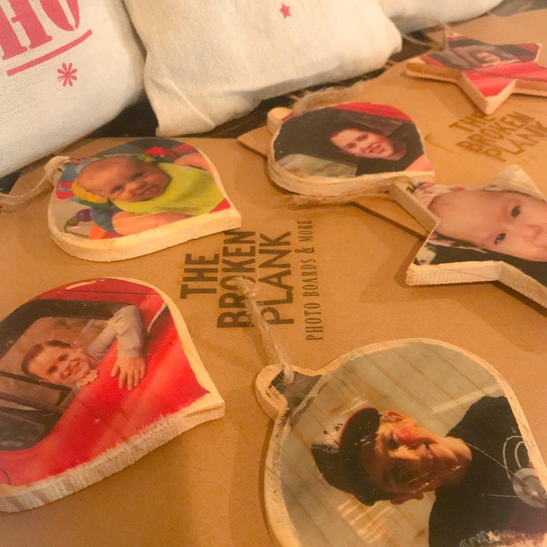 Wooden photo transfer ornaments in different shapes scattered on a brown surface near white pillows.