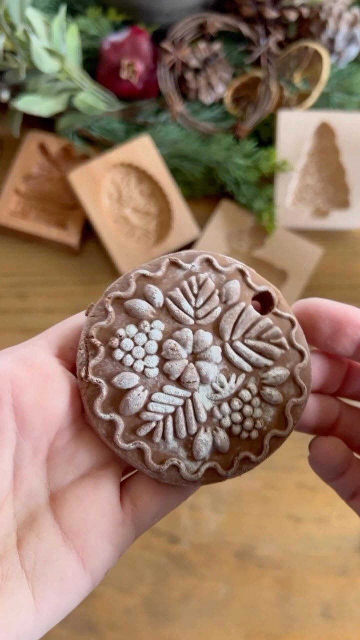 26 Handmade Ornaments: DIY Projects from Paper to Pinecones 3 Hands holding a round, patterned, brown scented ornament with floral designs.