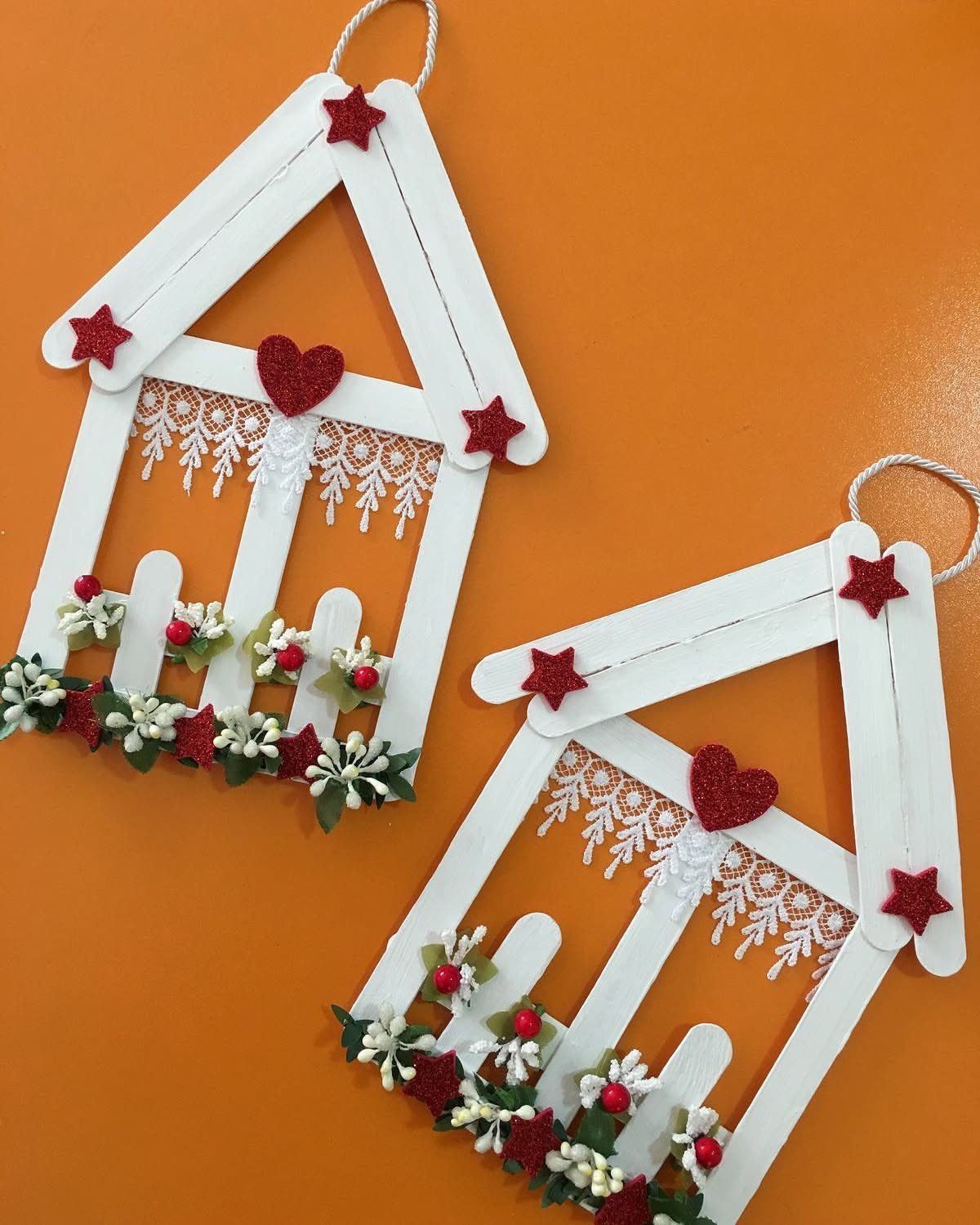 26 Handmade Ornaments: DIY Projects from Paper to Pinecones 23 Two white popsicle stick house ornaments decorated with red stars, hearts, lace, and tiny flowers.