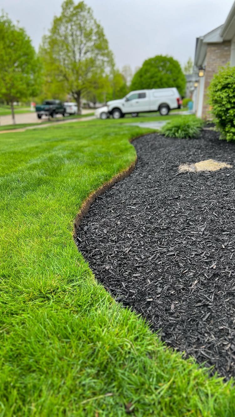 11 Inexpensive Landscaping Ideas for a Better Yard 5 Curved garden bed with dark mulch bordering a green lawn with defined edges.
