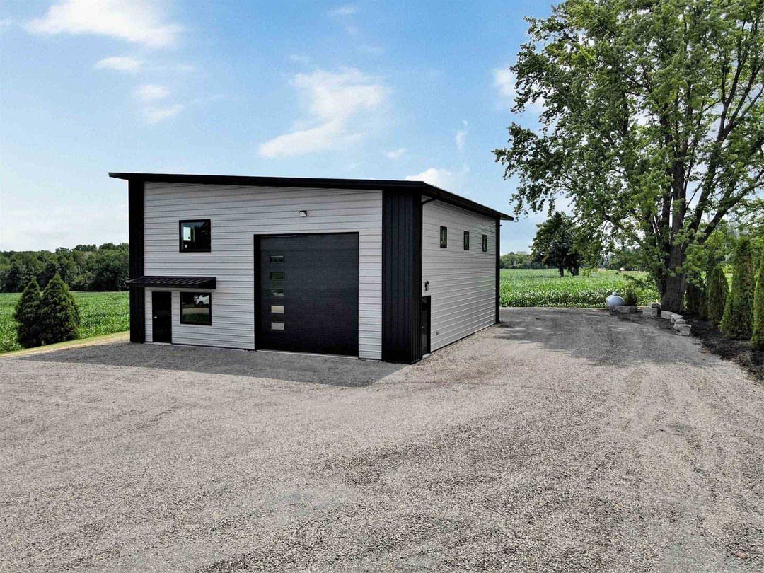 A modern white and black two-story garage building situated on a gravel lot under a blue sky.